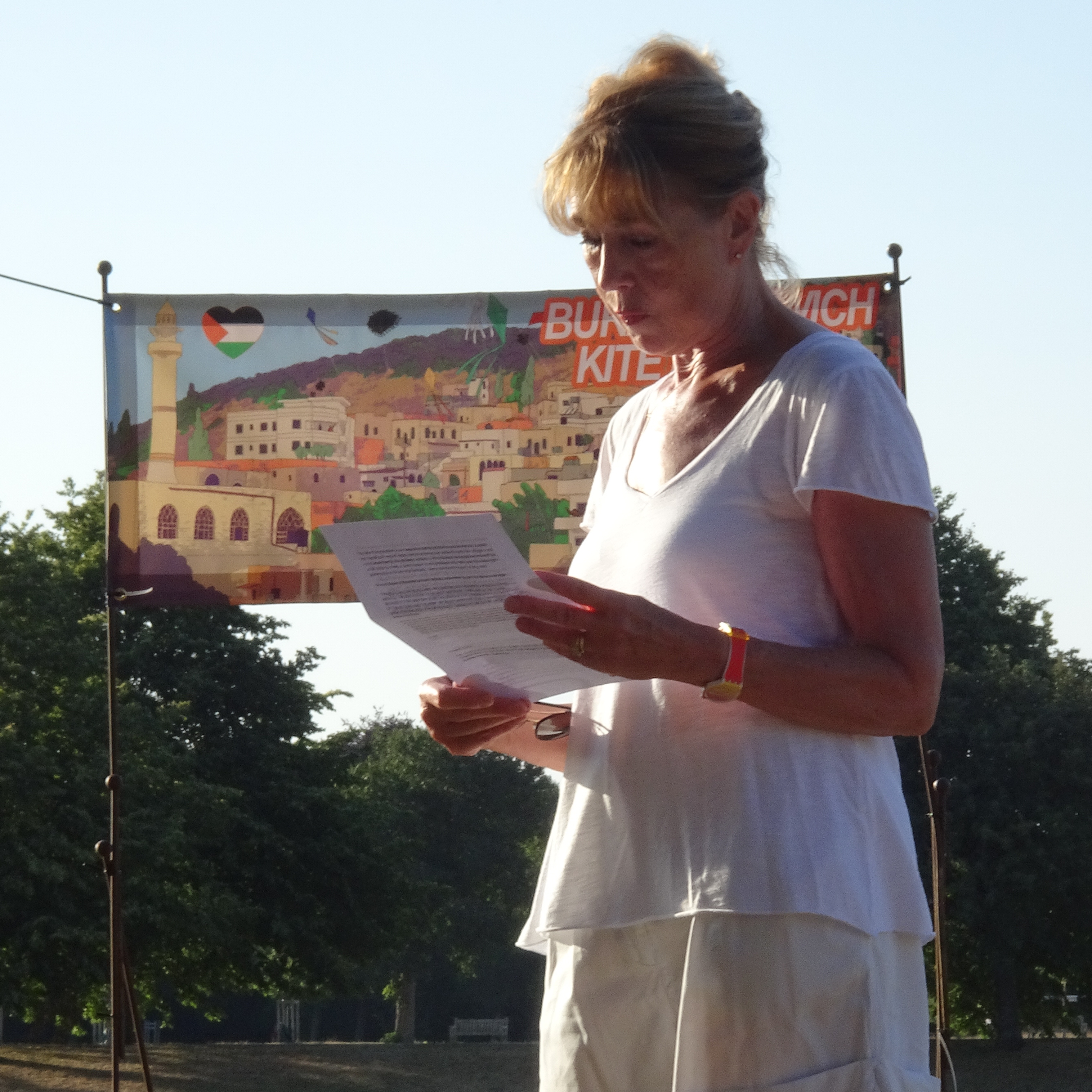 Linda Albin speaking in front of the Burin/Norwich Kite Festival banner.