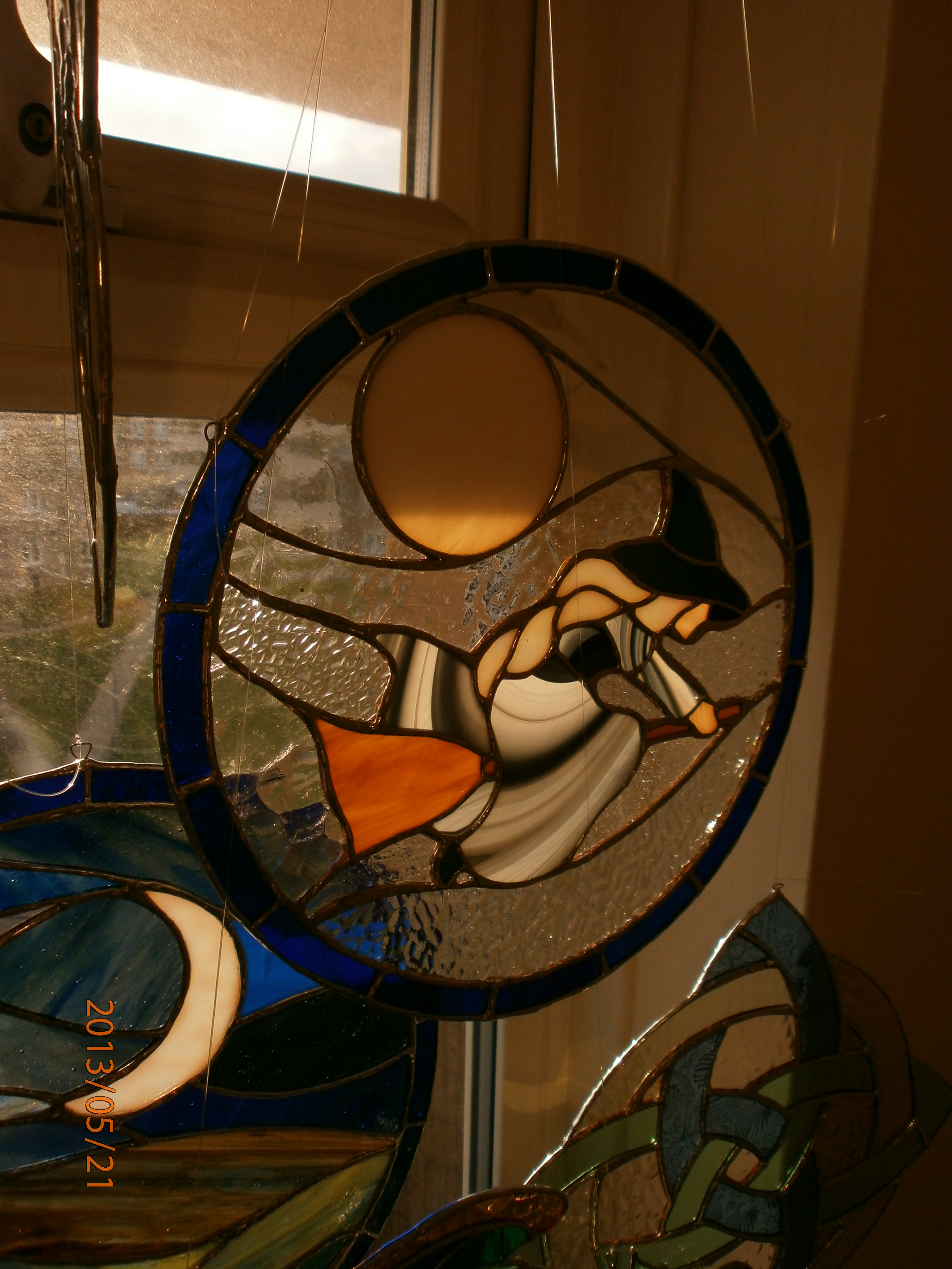 Image showing a stained glass hanger by Snapdragon Stained Glass, with a witch on a broomstick and a full moon behind. Picture by Lindy Osborne.