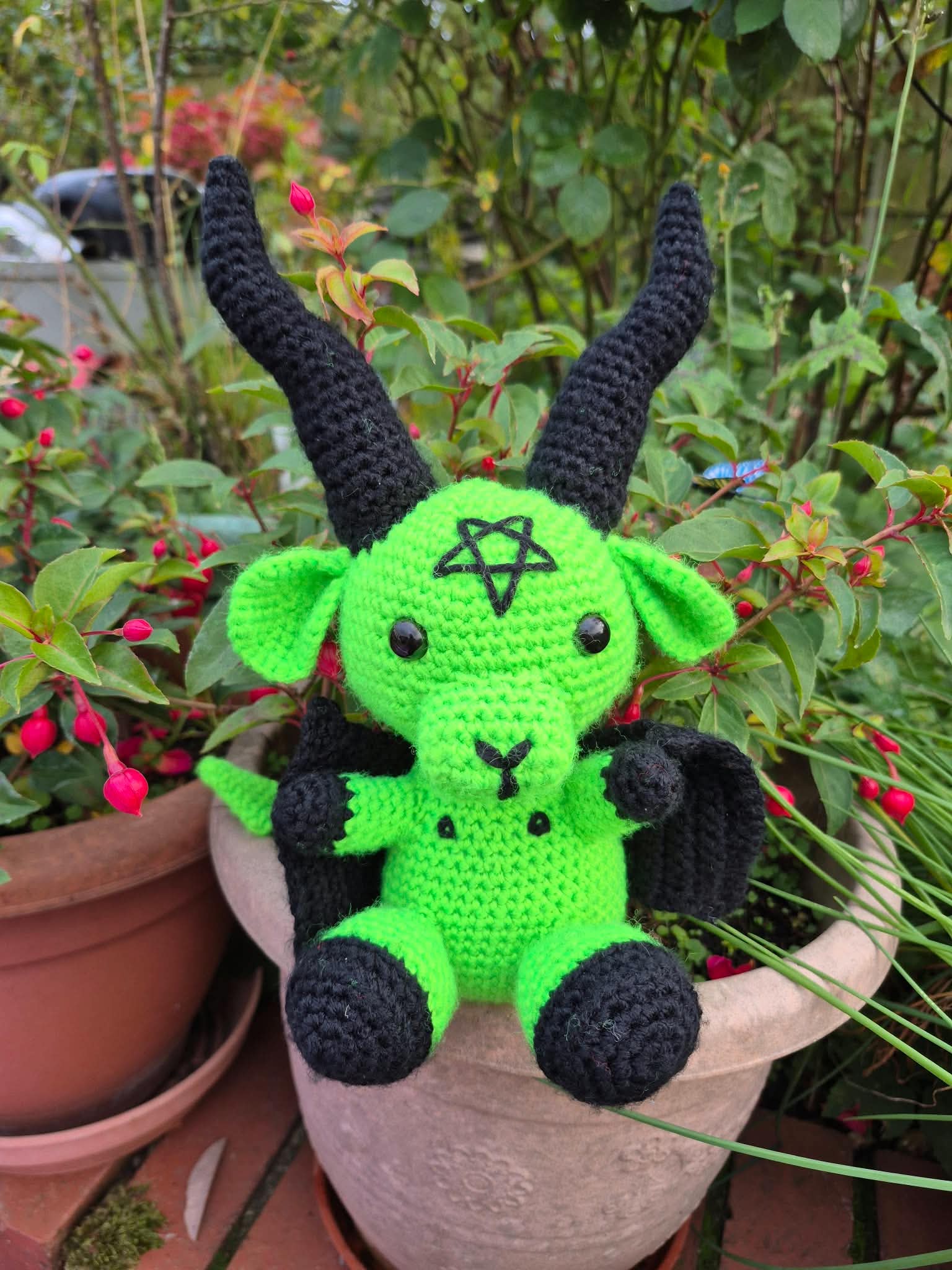 A demon teddy bear in green and black wool, with long black horns and an inverted pentagram on its forehead. Picture by Tina Hampton.