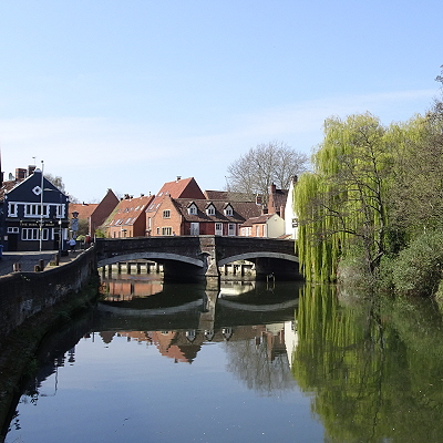 The river Wensum looking upstream at Fye Bridge, with the Ribs of Beef pub, housing and willows.